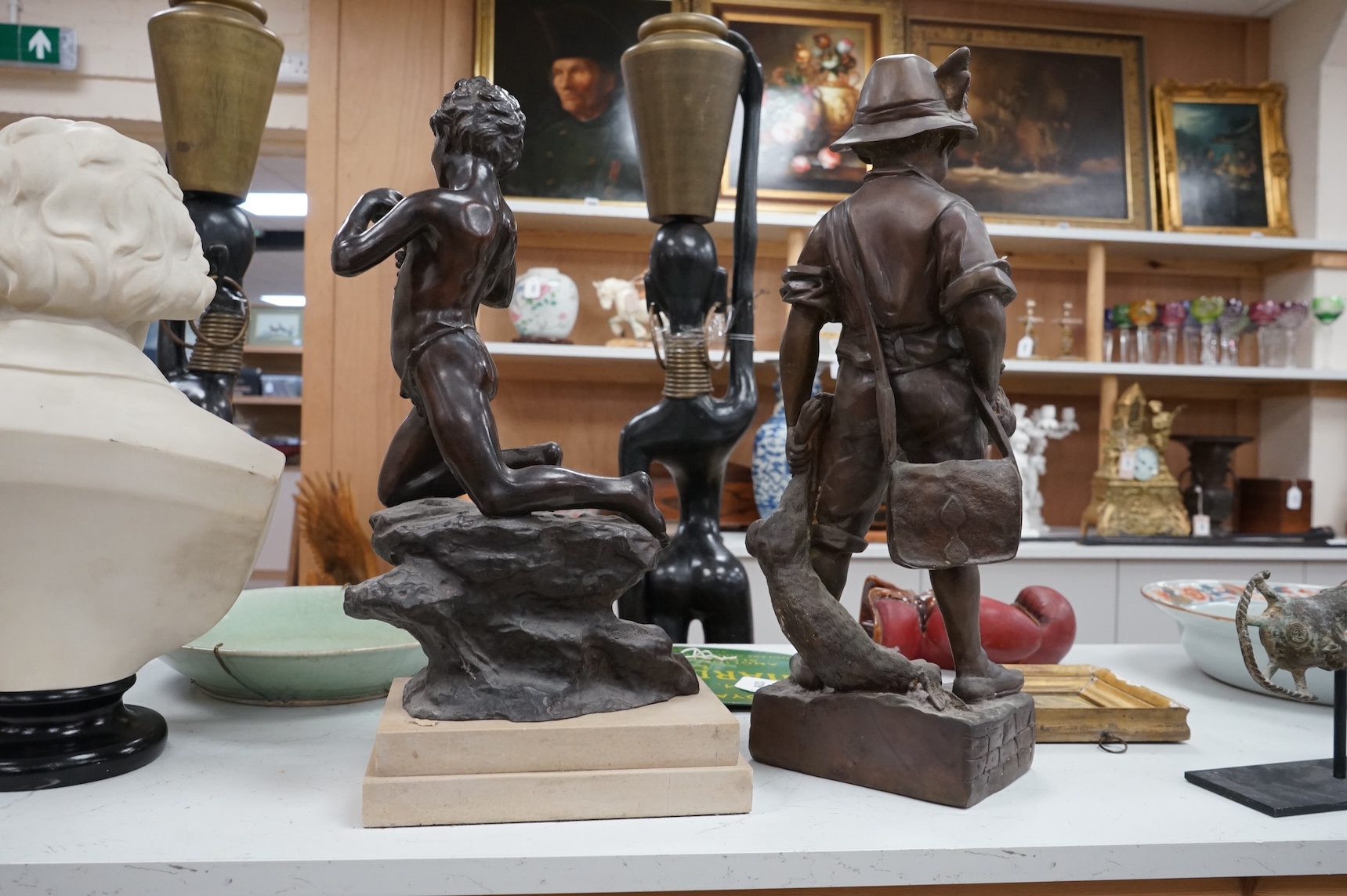 A bronze figure of a young boy carrying dead game, signed August, and a classic bronze of a young boy holding a fish, indistinctly signed, largest 53cm high